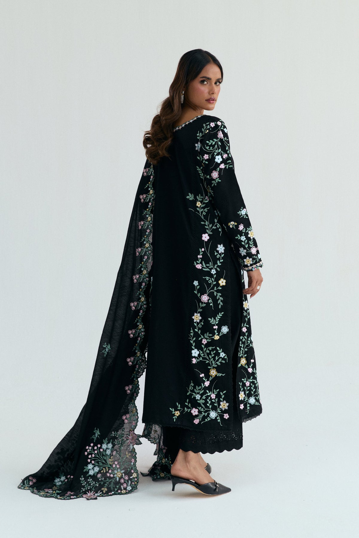 Back view showing cascading floral embroidery across full length of black cotton outfits