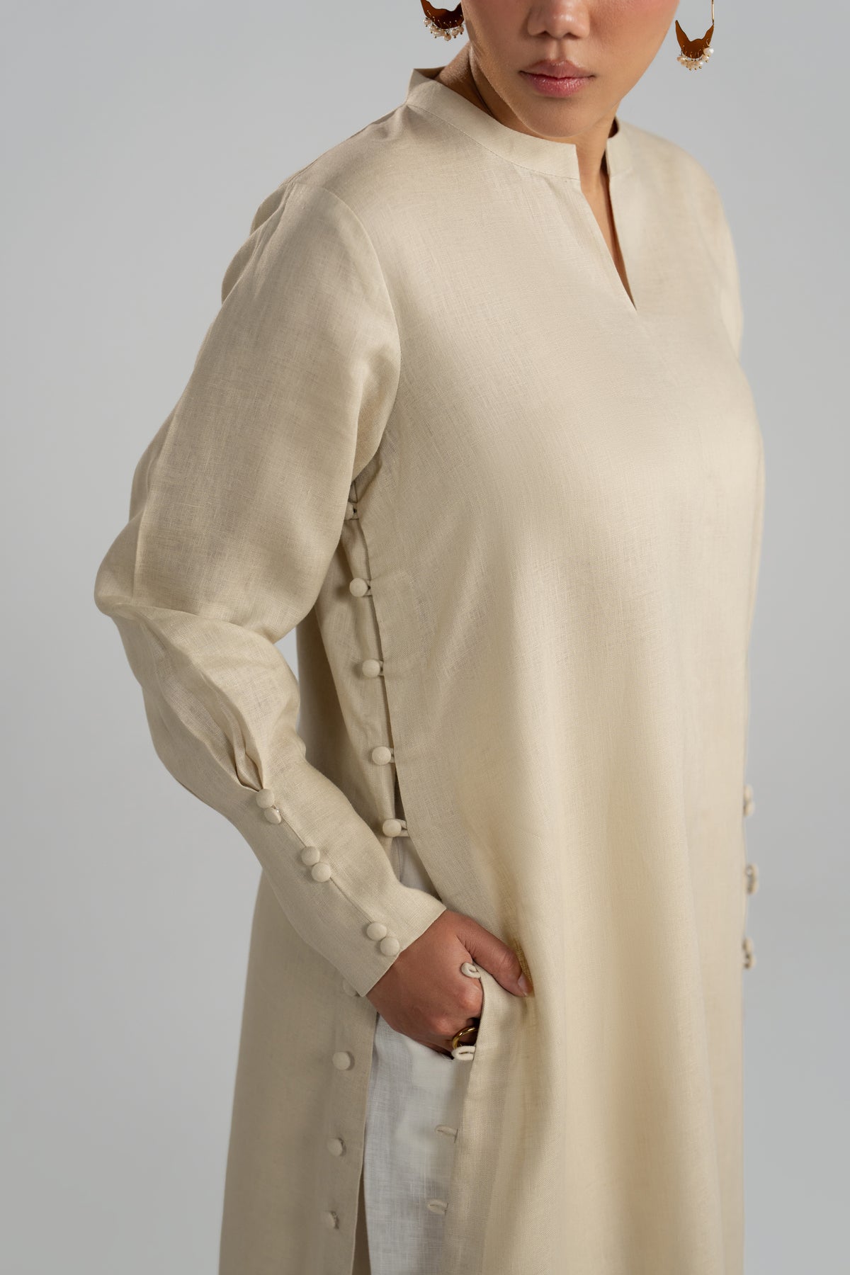 Close-up view of V-neckline, side stitched buttons and front slit detail