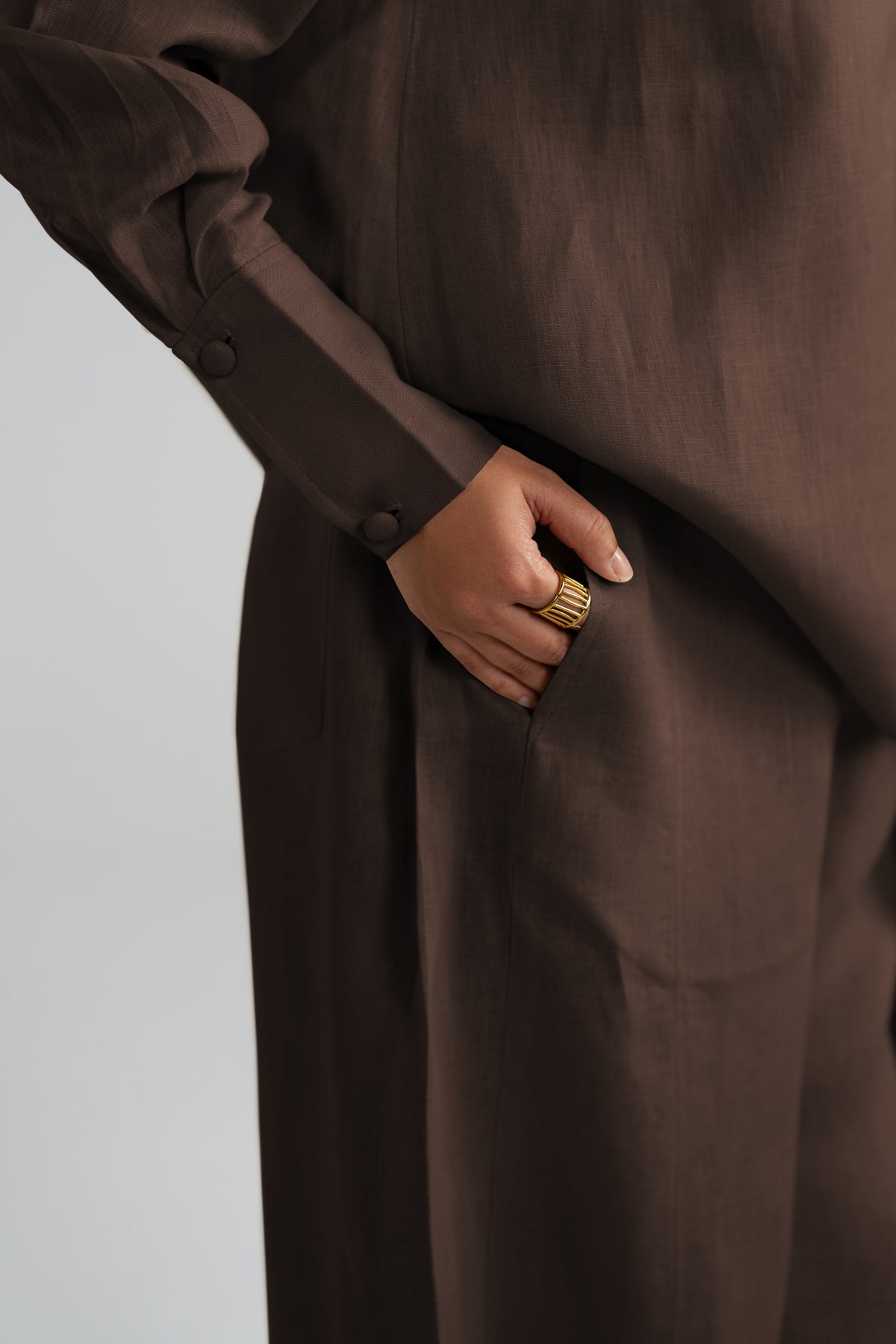 A close-up of a person wearing a dark brown long-sleeve dress or tunic with a side pocket.